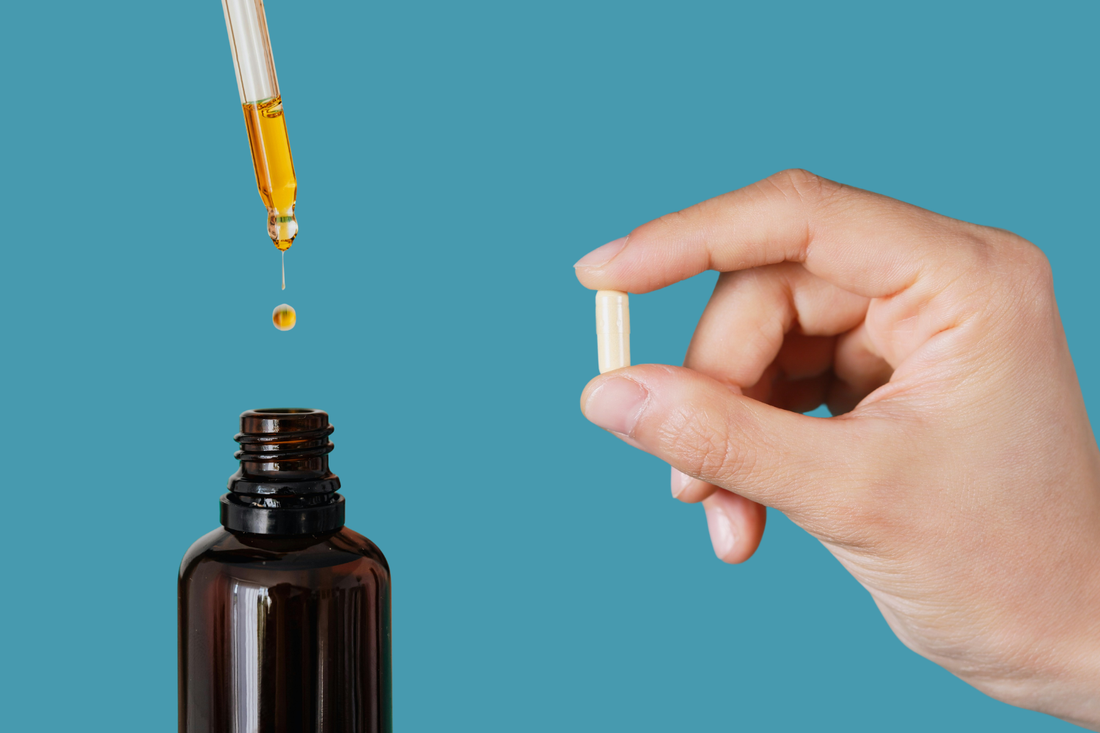 Hand holding lithium orotate capsule beside dropper adding liquid supplement into brown bottle on teal background, representing best lithium orotate supplement options
