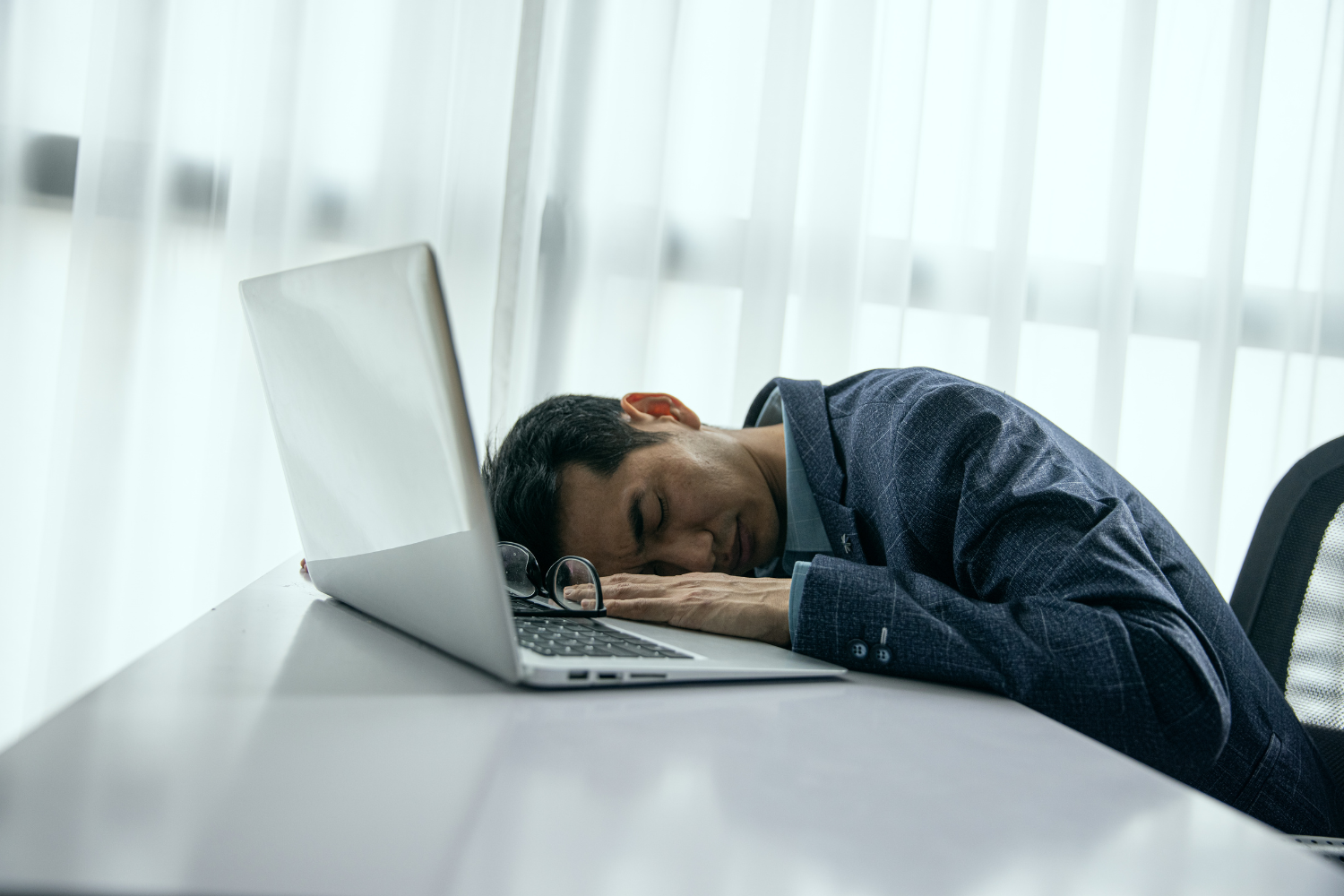 Tired businessman asleep on his laptop at a desk during the workday