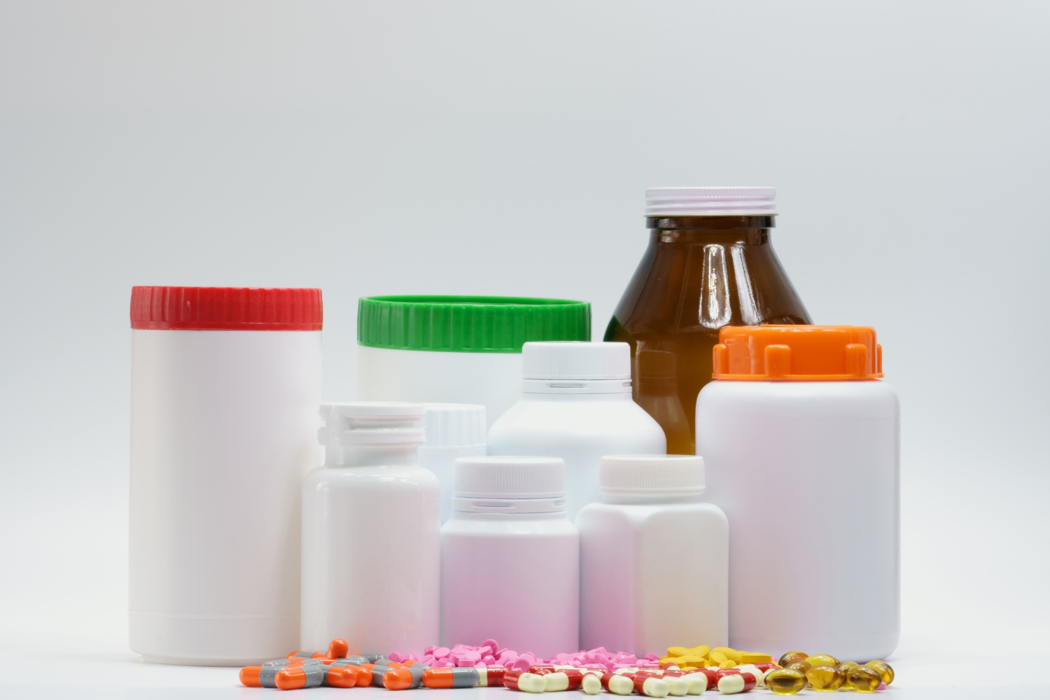 Assorted medicine bottles and scattered colorful pills on a white background