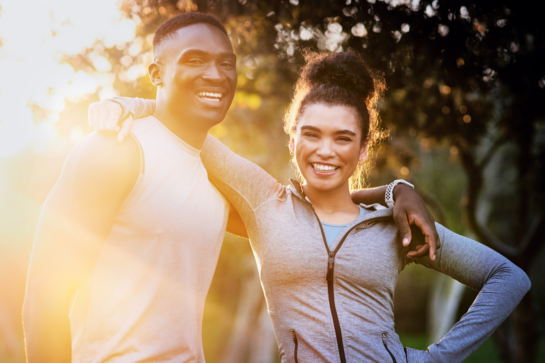 Two people smiling outdoors with an arm around the shoulder, symbolizing emotional wellness through connection, positivity, and support.