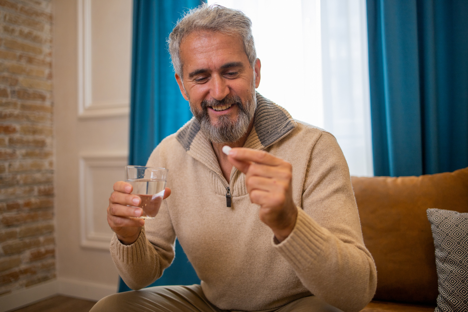 Man holding a supplement tablet and glass of water at home