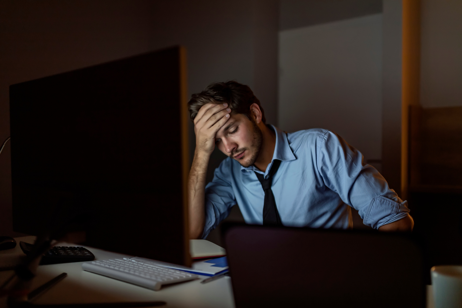 Tired man resting his head at a desk late at night during a stressful workday