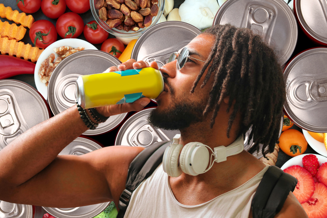 Man drinking an energy drink surrounded by fresh foods and cans, illustrating how to compare caffeine, sugar, and ingredients when choosing a healthier energy drink.