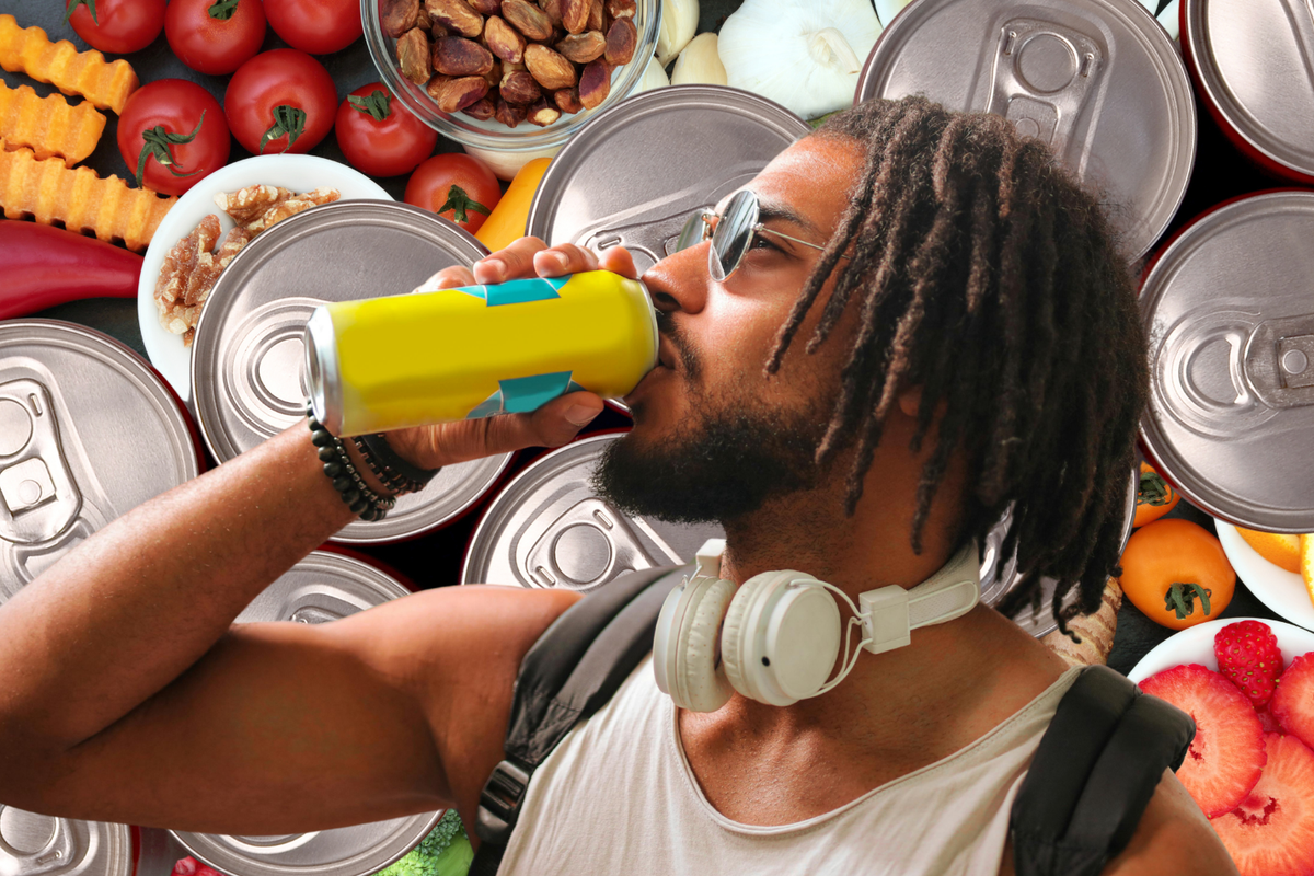 Man drinking an energy drink surrounded by fresh foods and cans, illustrating how to compare caffeine, sugar, and ingredients when choosing a healthier energy drink.