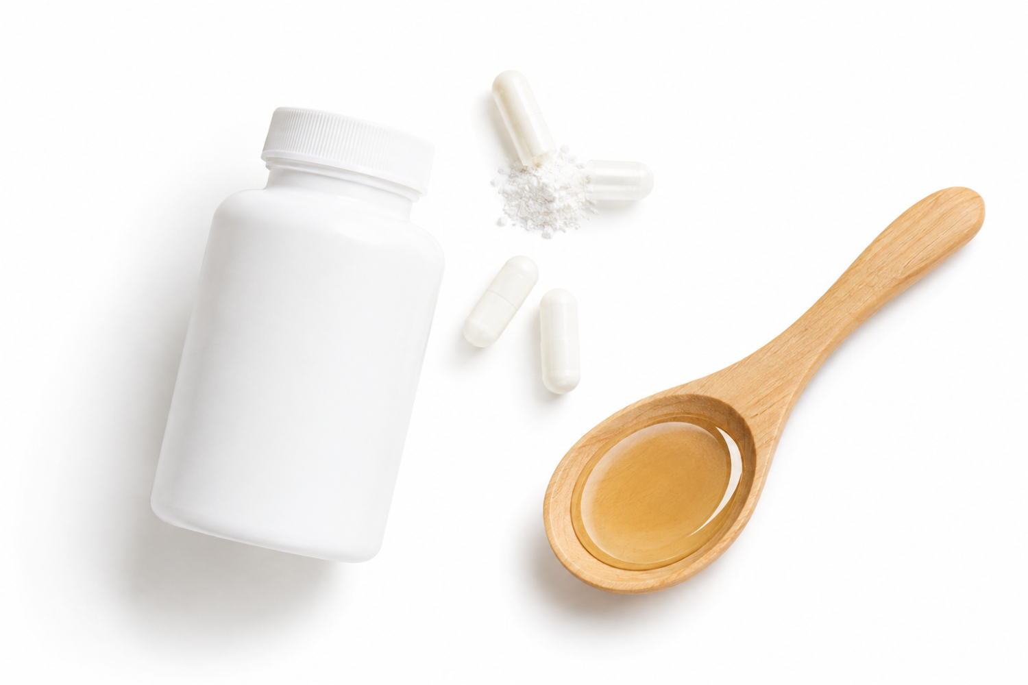 White plastic bottle with a few scattered white capsules above it, and a wooden spoon filled with golden powder on a clean white background.