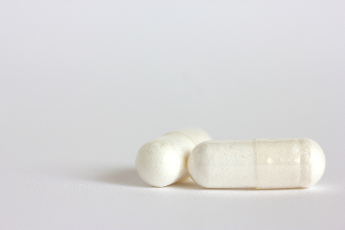 Two white supplement capsules on a light background representing lithium orotate 5mg and 10mg dosage options.