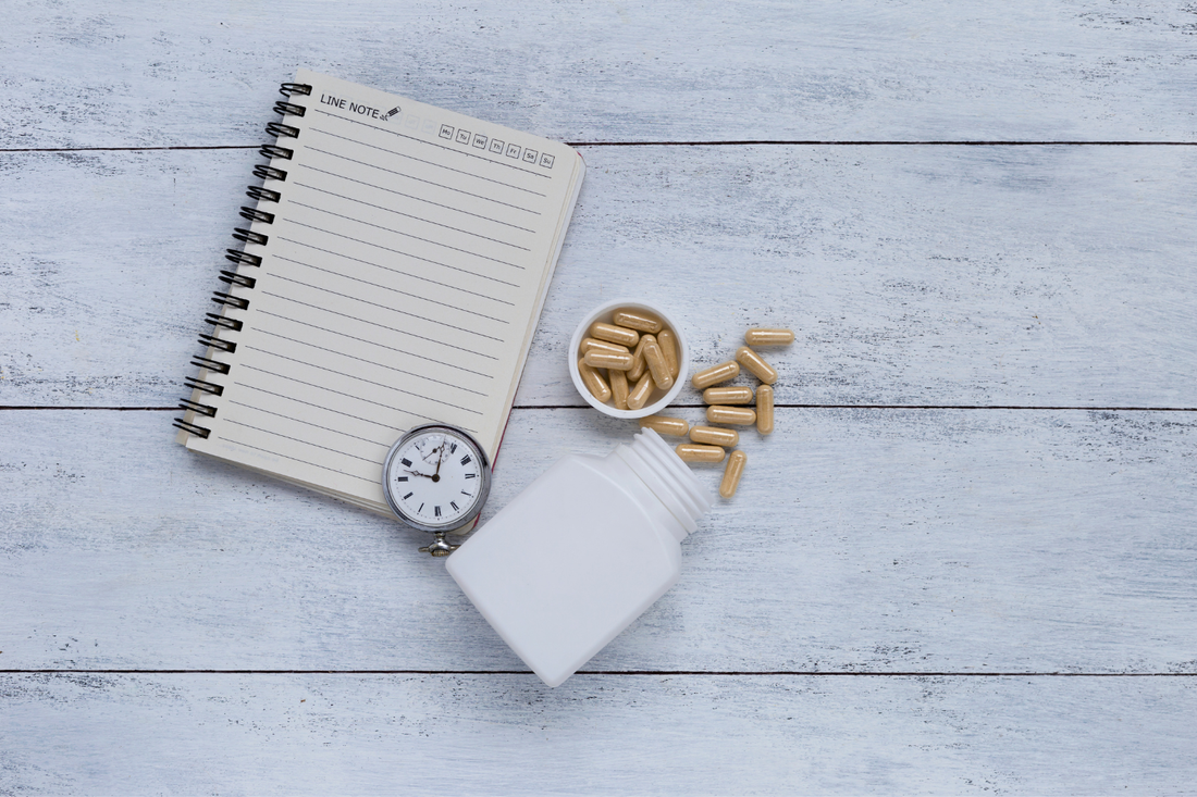 Lithium orotate capsule and bottle beside a clock and a notebook.