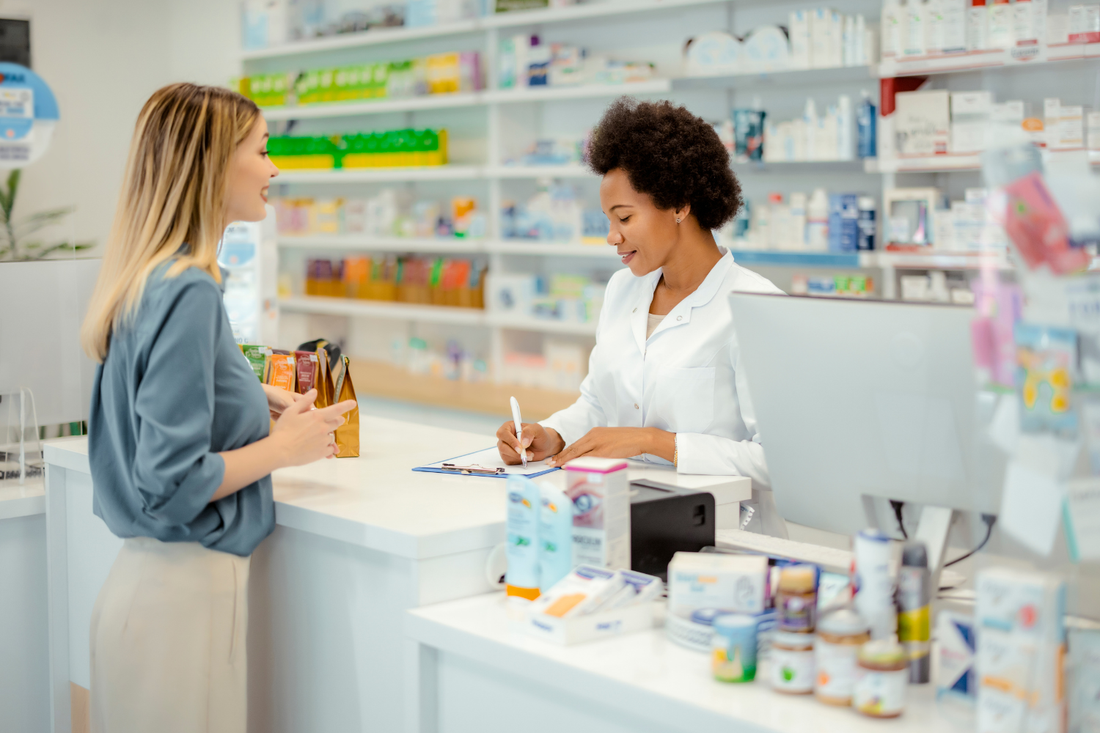 Customer speaking with a pharmacist at a pharmacy counter while comparing supplement options for an over-the-counter lithium buying guide.